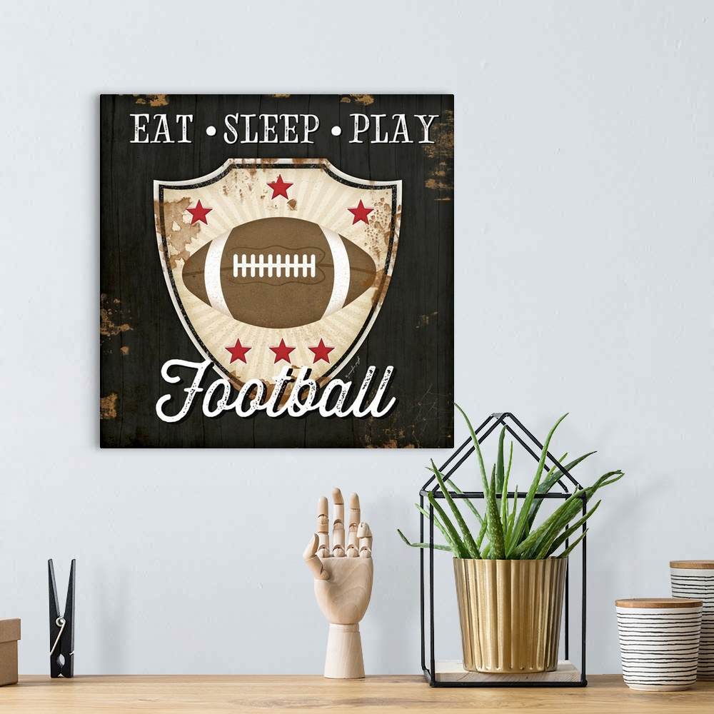 A bohemian room featuring Distressed themed artwork of football with the words, "Eat, Sleep, Play Football" .