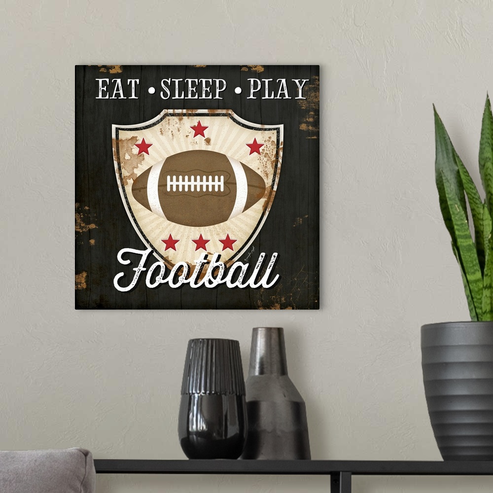 A modern room featuring Distressed themed artwork of football with the words, "Eat, Sleep, Play Football" .