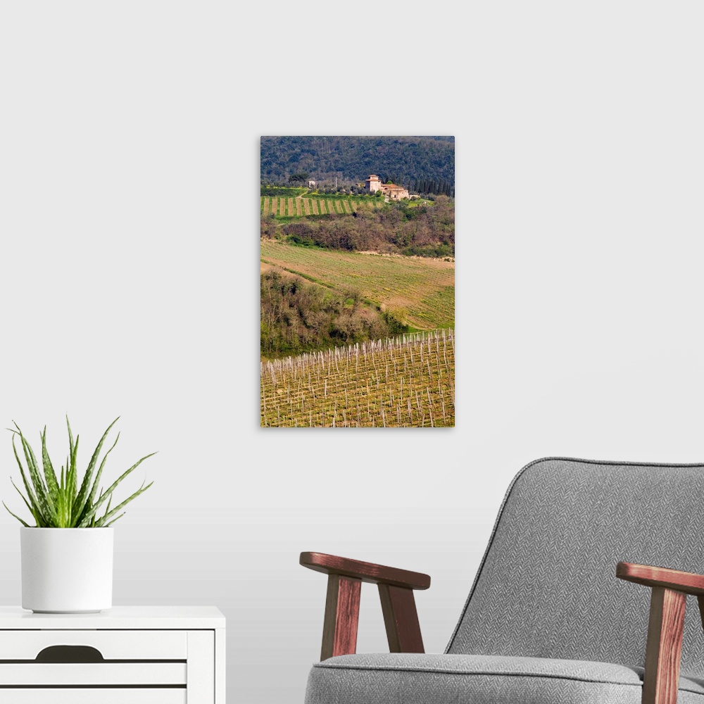 A modern room featuring A grand stone winery stands above rolling vineyards, Chianti, Tuscany, Italy.