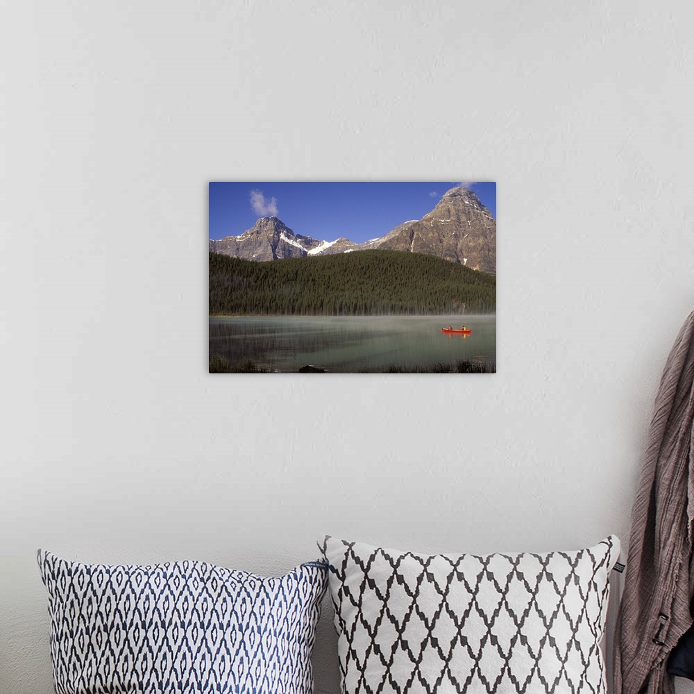 A bohemian room featuring Two boys fishing from a red canoe in Waterfowl Lake, in Canada's Banff national park.