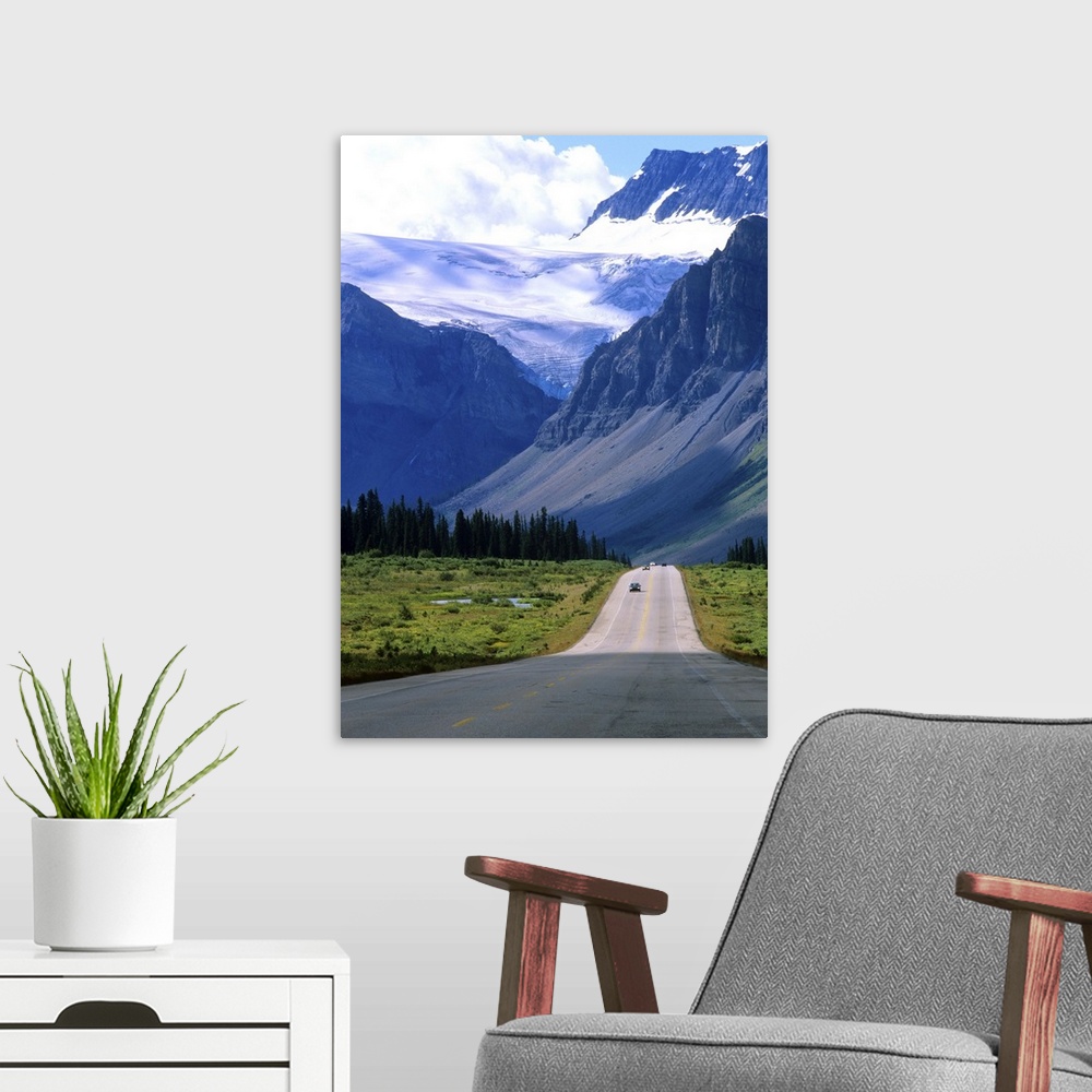 A modern room featuring A road into the mountains of Banff National Park, where fierce clouds and snowcapped peaks loom i...
