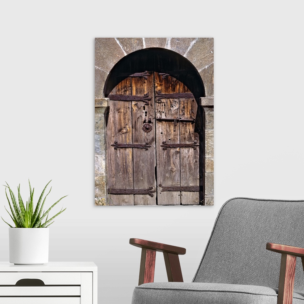A modern room featuring Europe, Andorra. An ancient old wooden door contrasts against a stone building in Andorra.