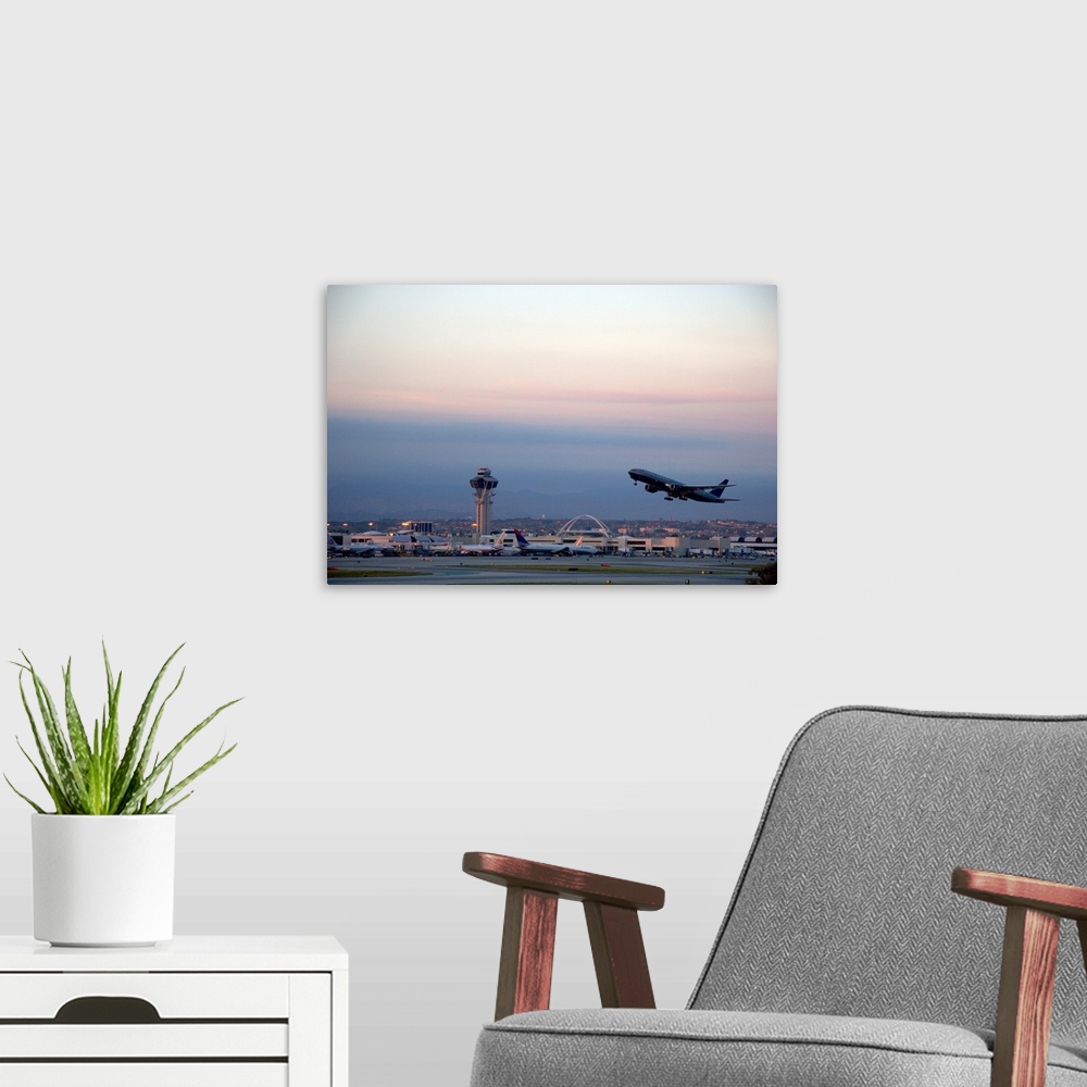 A modern room featuring Boeing 767 airplane taking off at LAX airport, Los Angeles, California at dusk.
