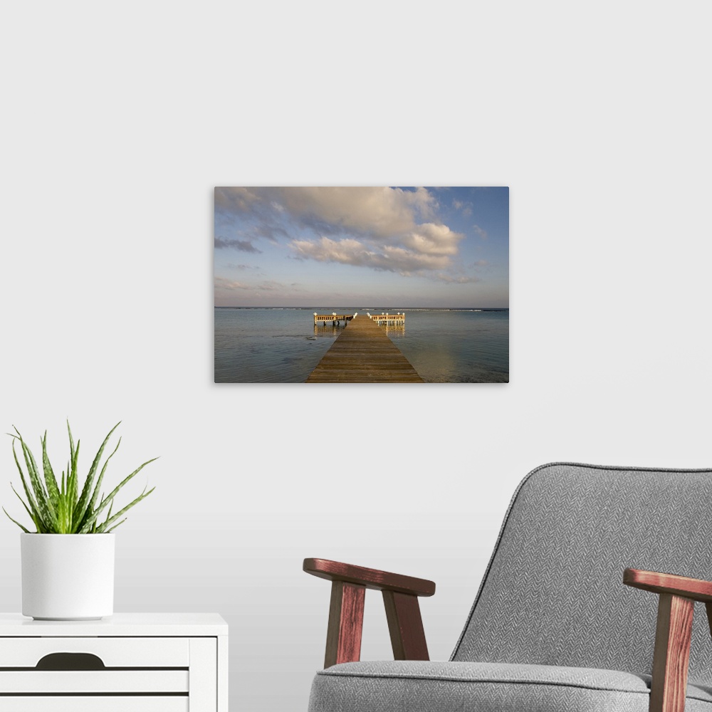 A modern room featuring Cayman Islands, Little Cayman Island, Setting sun lights wooden boat pier in Caribbean Sea
