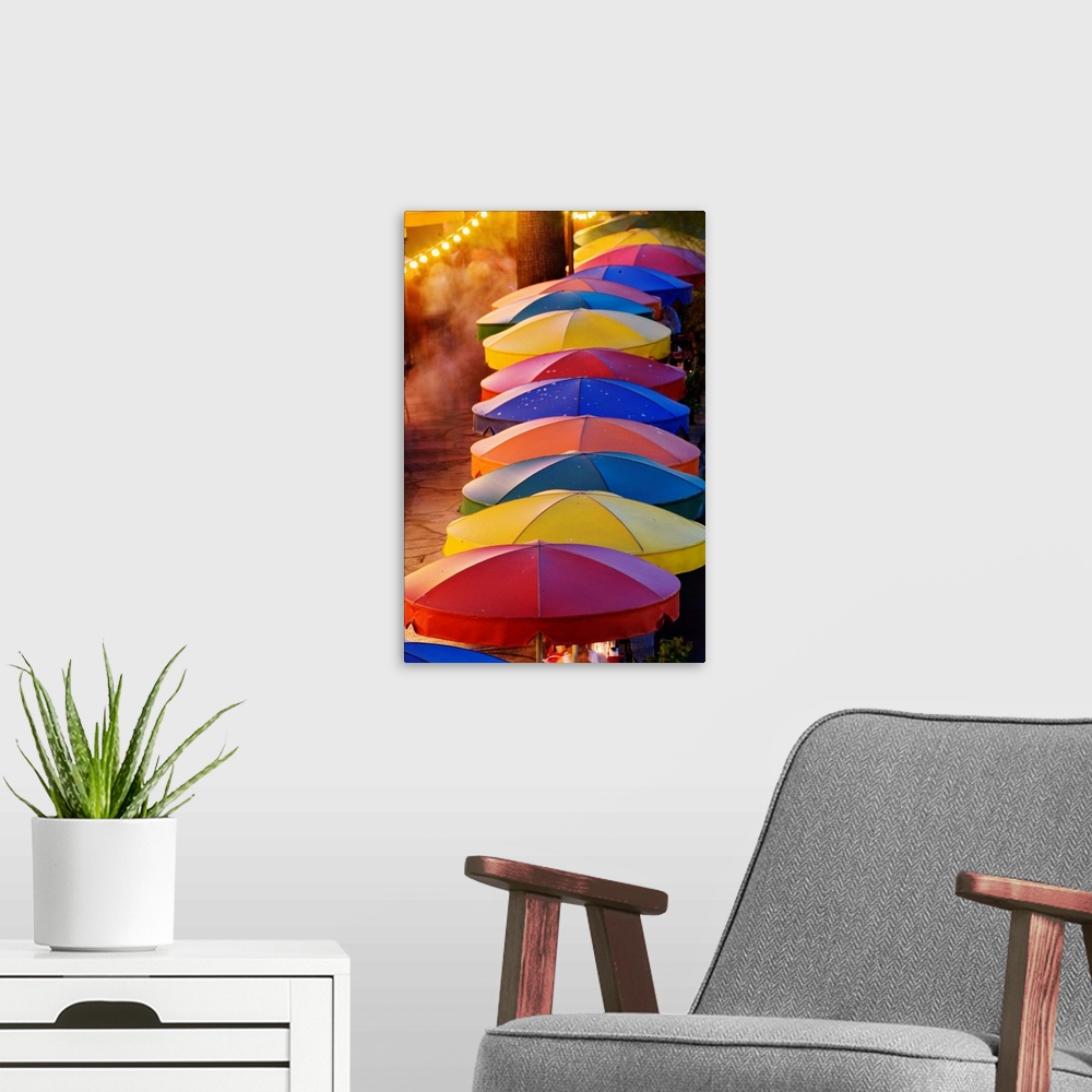 A modern room featuring Colorful umbrellas of outdoor cafe and blurred people in motion along famous River Walk and San A...
