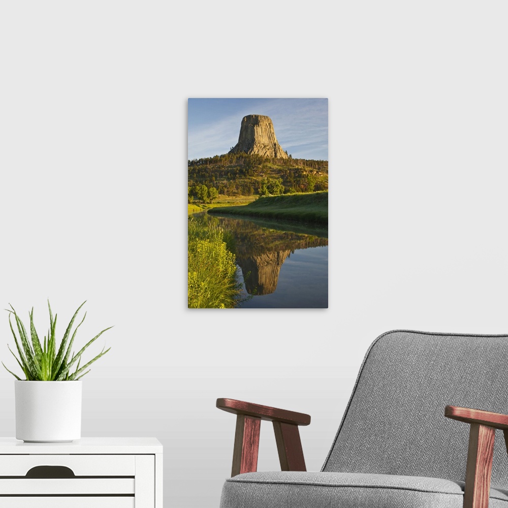 A modern room featuring Devil's Tower National Monument, Wyoming, reflected in Belle Fourche River at sunrise.