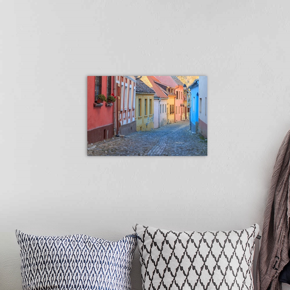 A bohemian room featuring Europe, Romania, Sighisoara, cobblestone residential street of colorful houses in village. UNESCO...