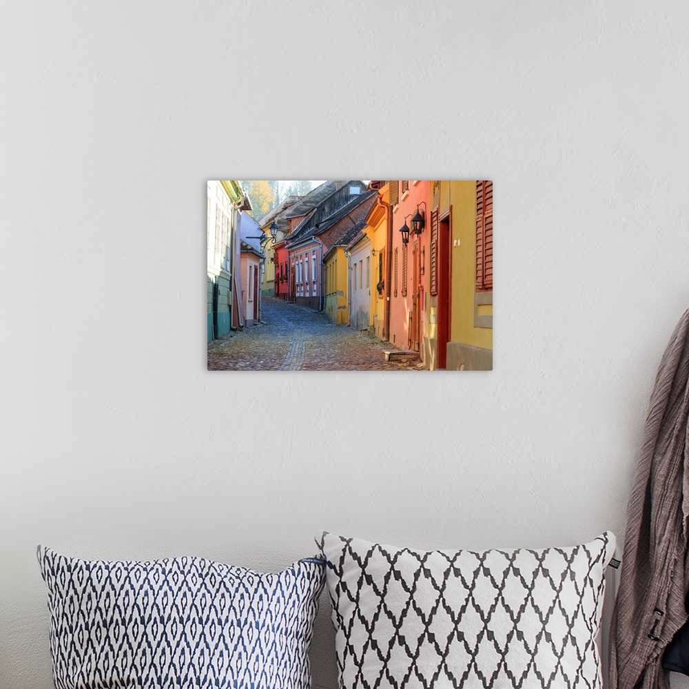 A bohemian room featuring Europe, Transylvania, Romania, Mures County, Sighisoara, cobblestone residential street of colorf...