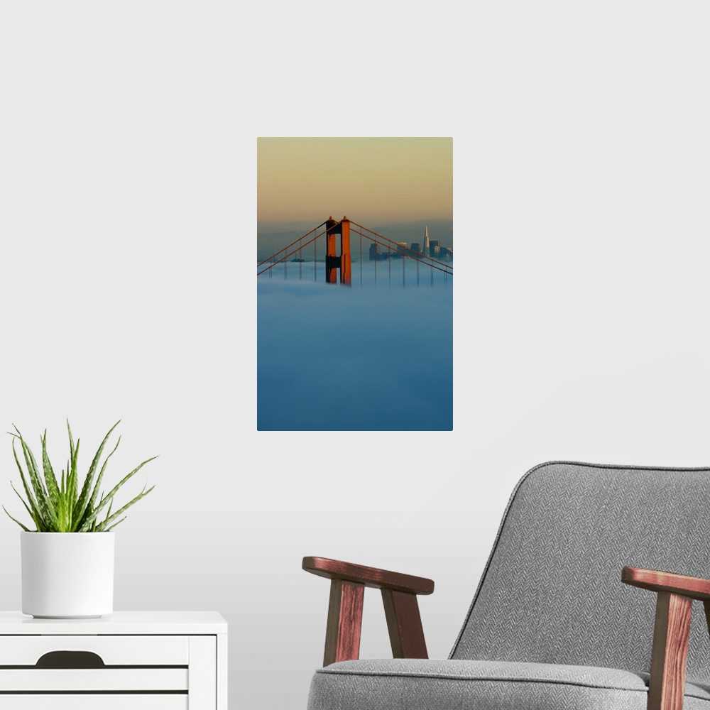 A modern room featuring Fog rolls through the San Francisco bay covering the Golden Gate Bridge and city. Pictured is the...