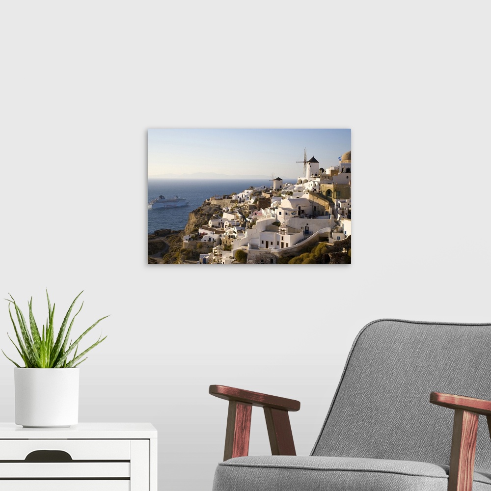 A modern room featuring Greece and Greek Island of Santorini town of Oia in evening light with the many homes and busines...