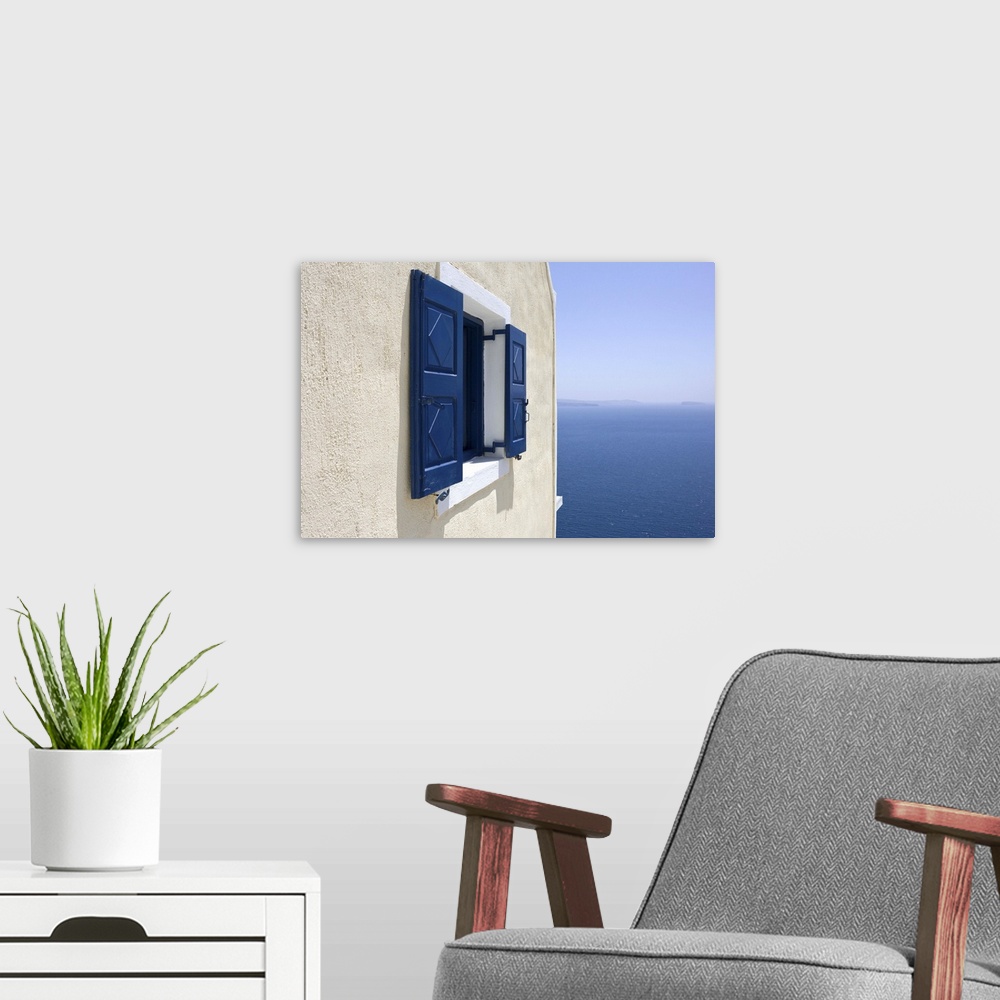 A modern room featuring Europe, Greece, Santorini, Thira, Oia. Blue-shuttered window in pale yellow wall overlooking blue...