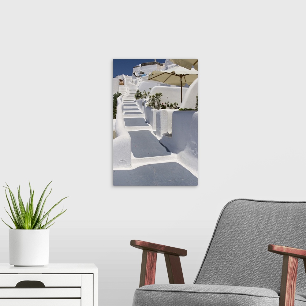 A modern room featuring Europe, Greece, Santorini, Thira, Oia. Grey and white painted stairs leading past open patio umbr...
