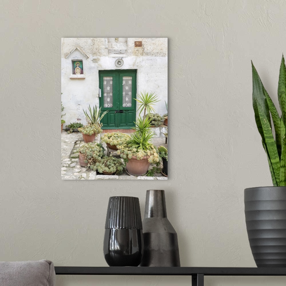 A modern room featuring Italy, Basilicata, Matera. Plants adorn the outside walls of the Sassi houses.