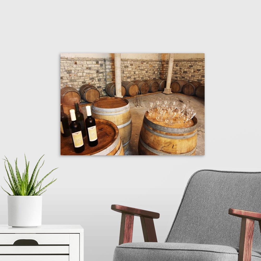A modern room featuring Oak barrels and bottles and glasses set up for a tasting. Cobo winery, Poshnje, Berat. Albania, B...