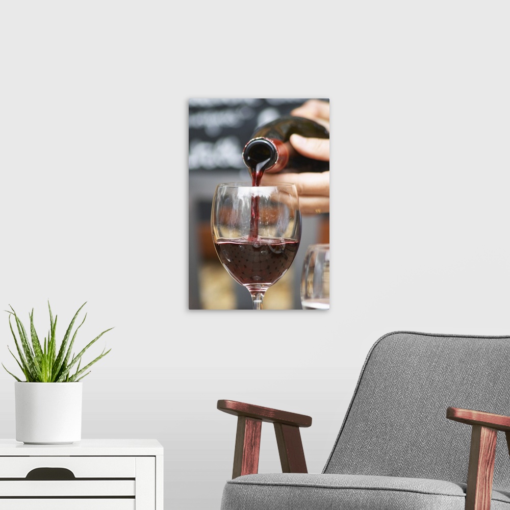 A modern room featuring Red chateauneuf wine being poured from a bottle into a glass. The restaurant Le Verger de Papes i...