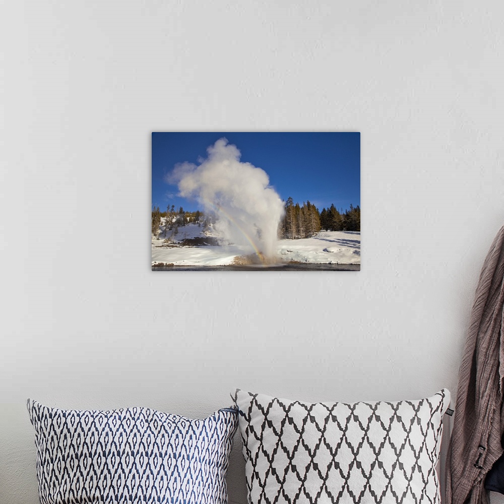 A bohemian room featuring Riverside Geyser erupts along the Firehole River on a nice sunny winter day in Yellowstone Nation...