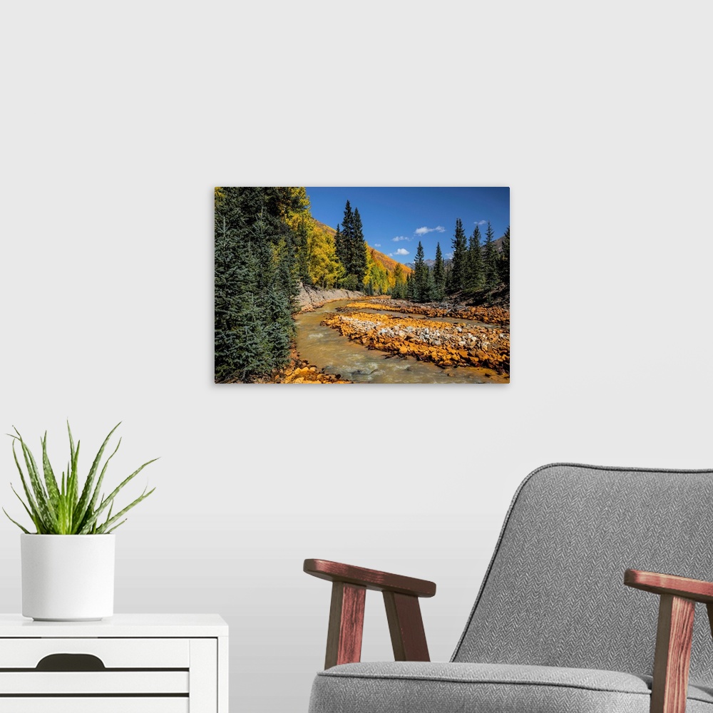 A modern room featuring Rusted red rocks along Ironton Creek of golden autumn aspen trees and evergreens, ghost town of I...