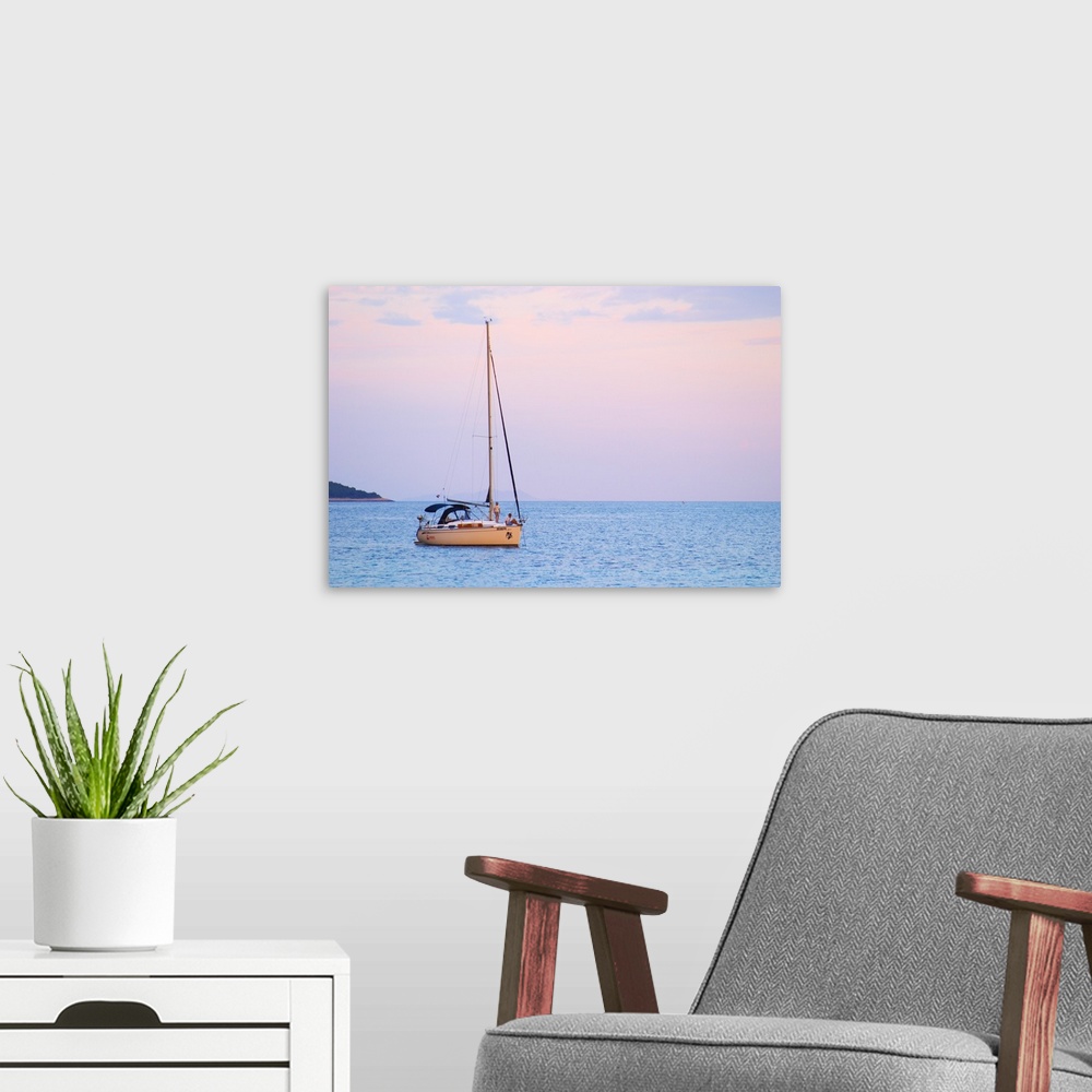 A modern room featuring A sailing boat moored in the bay with two people on the deck off Korcula at sunset. Prizba villag...