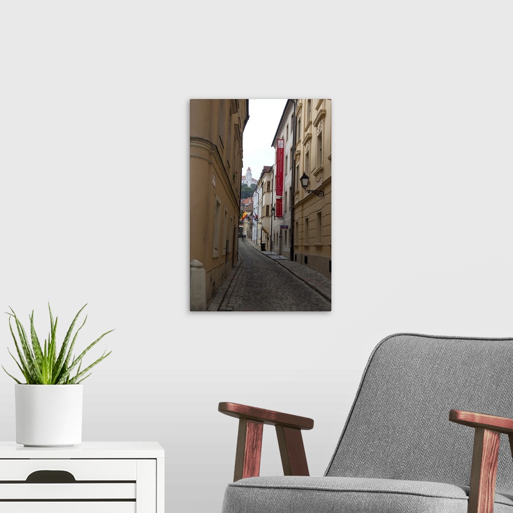 A modern room featuring Slovakia, Bratislava. Narrow street in historic district with view of Bratislava Castle in distance.