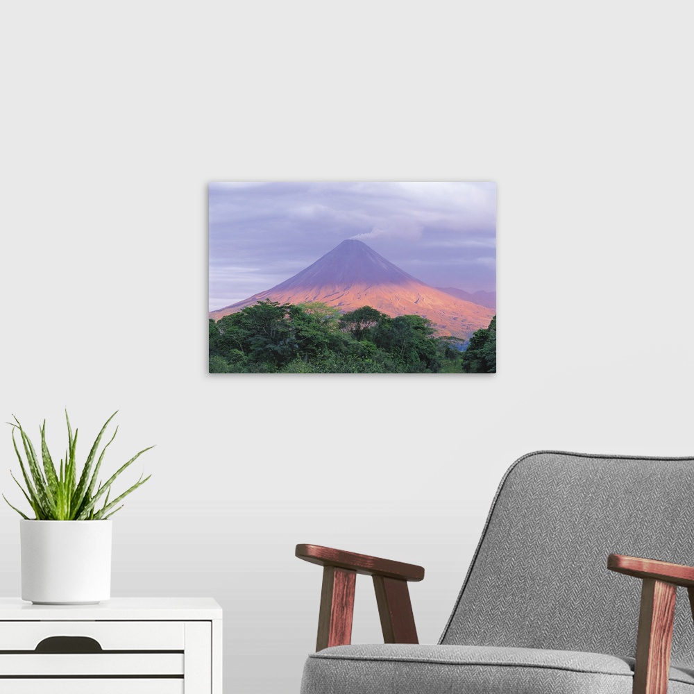 A modern room featuring Sunset light peers through the clouds to illuminate the flanks of Arenal Volcano (1,670m/5,479ft)...