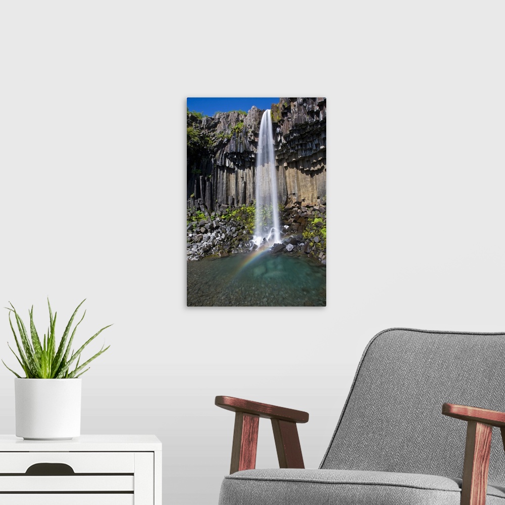 A modern room featuring Svartifoss, a waterfall in southern Iceland, cascades over ancient basaltic columns.