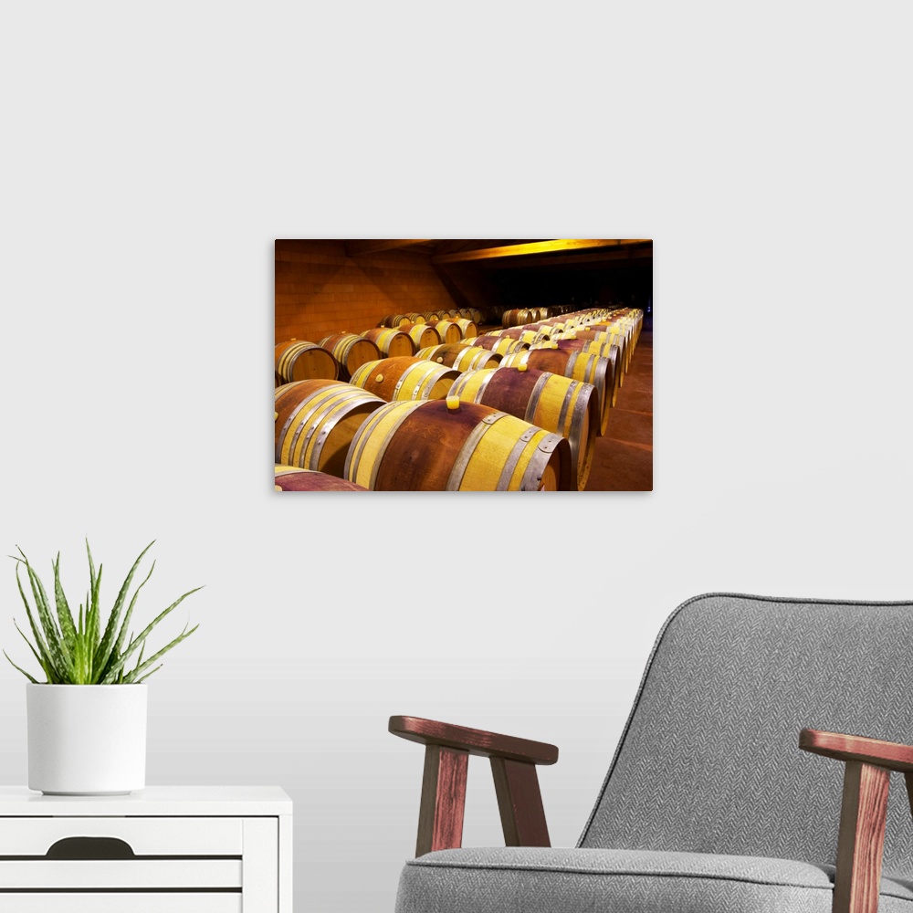 A modern room featuring The barrel aging cellars with rows of oak barrels. All are "painted" red in the middle with red w...