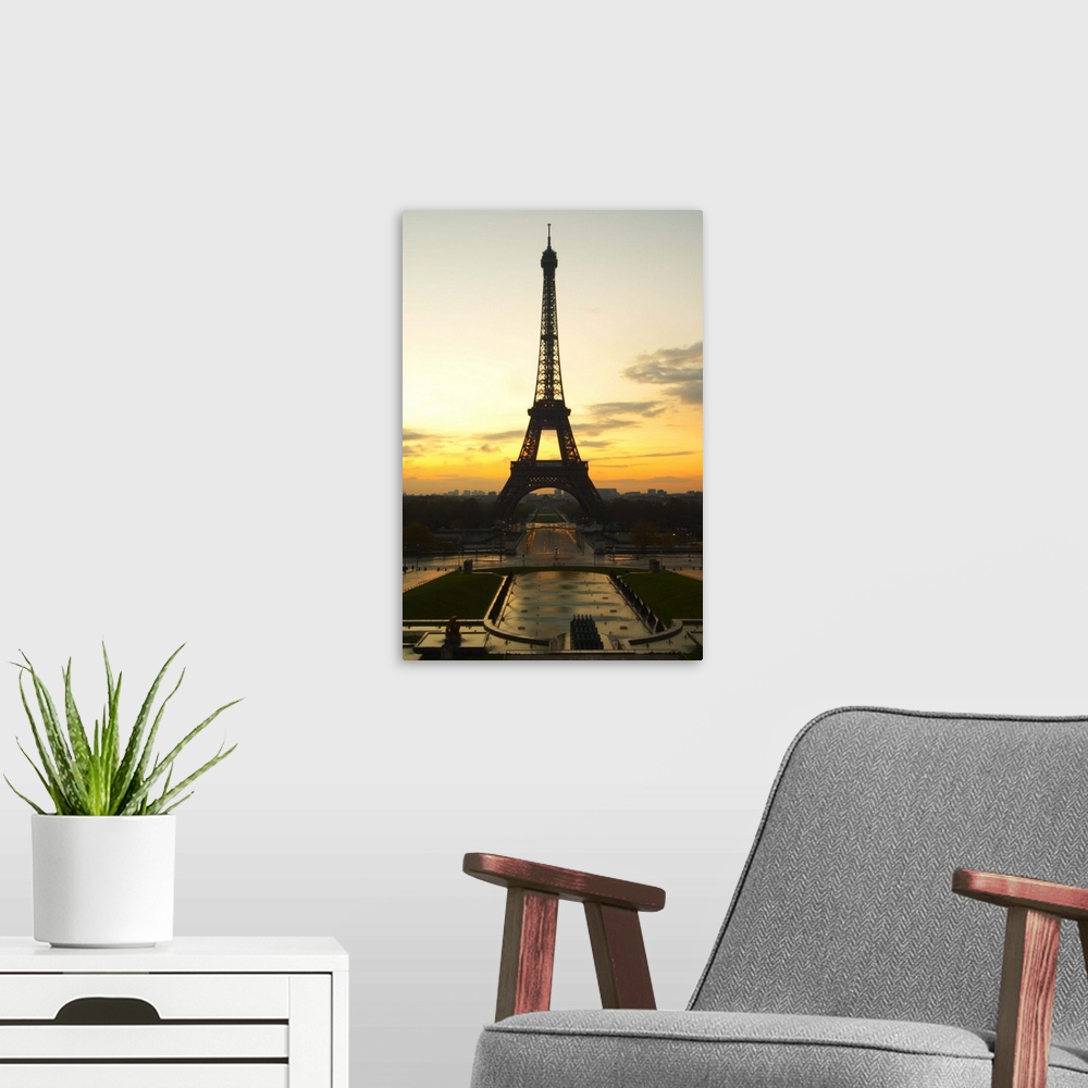A modern room featuring The Eiffel Twoer in Paris in early morning dawn with the sun rising on the horizon, pale blue sky...