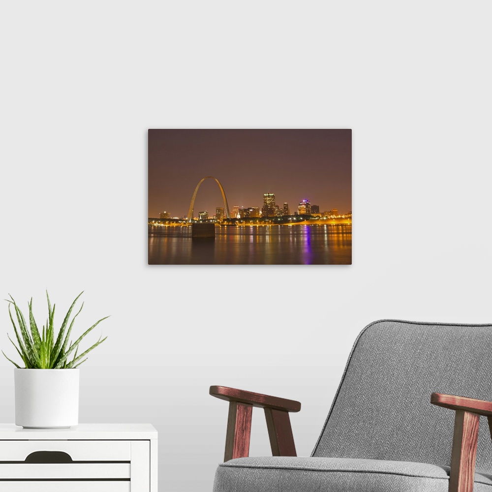A modern room featuring The Gateway Arch and St Louis skyline reflect into the Mississippi River at dusk in St Louis, Mis...