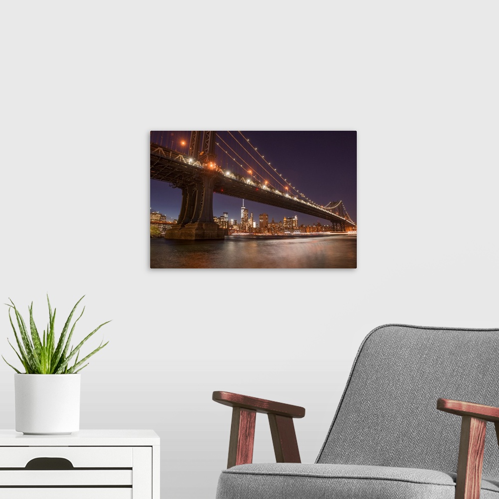A modern room featuring The Manhattan Bridge and Manhattan skyline in the evening light from Brooklyn Bridge Park, New Yo...