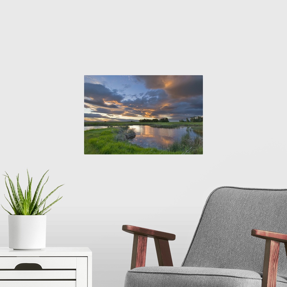 A modern room featuring Vivid sunset clouds reflect into small pond at the Ninepipe Wildlife Management Area in the Missi...