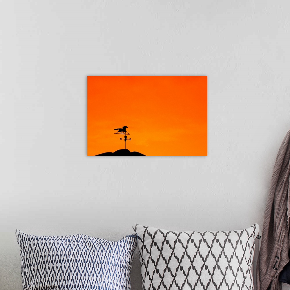 A bohemian room featuring Weathervane atop barn at sunset indicates wind direction