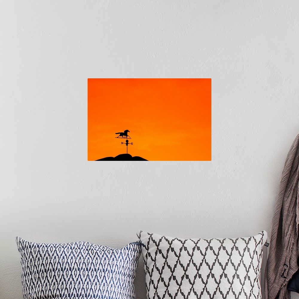 A bohemian room featuring Weathervane atop barn at sunset indicates wind direction