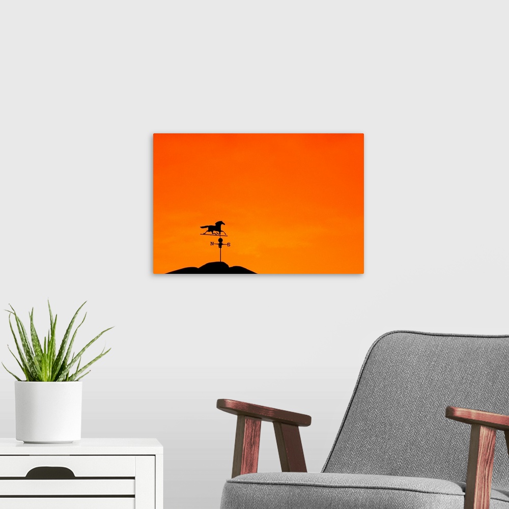 A modern room featuring Weathervane atop barn at sunset indicates wind direction