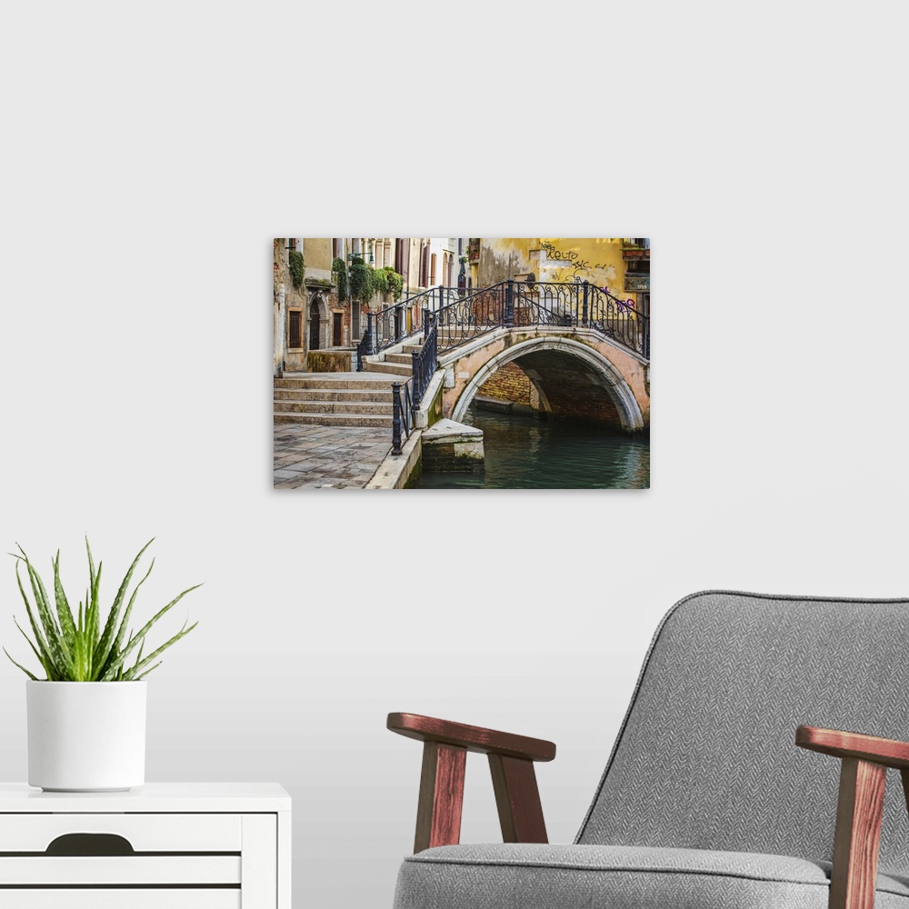A modern room featuring Narrow canal among old colorful brick houses in Venice, Italy.