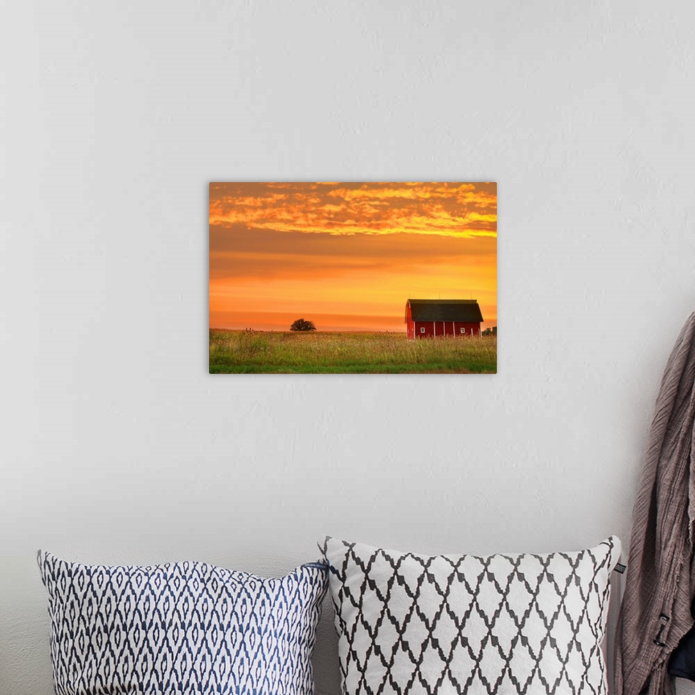 A bohemian room featuring Farm landscape with old barn against bright evening sky.
