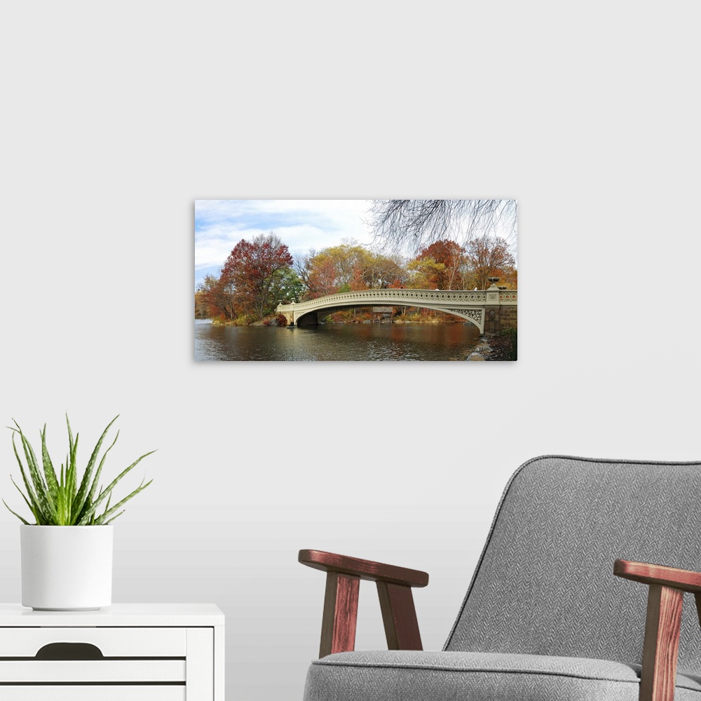 A modern room featuring Central Park panorama in autumn with skyscrapers, foliage, lake and Bow Bridge.