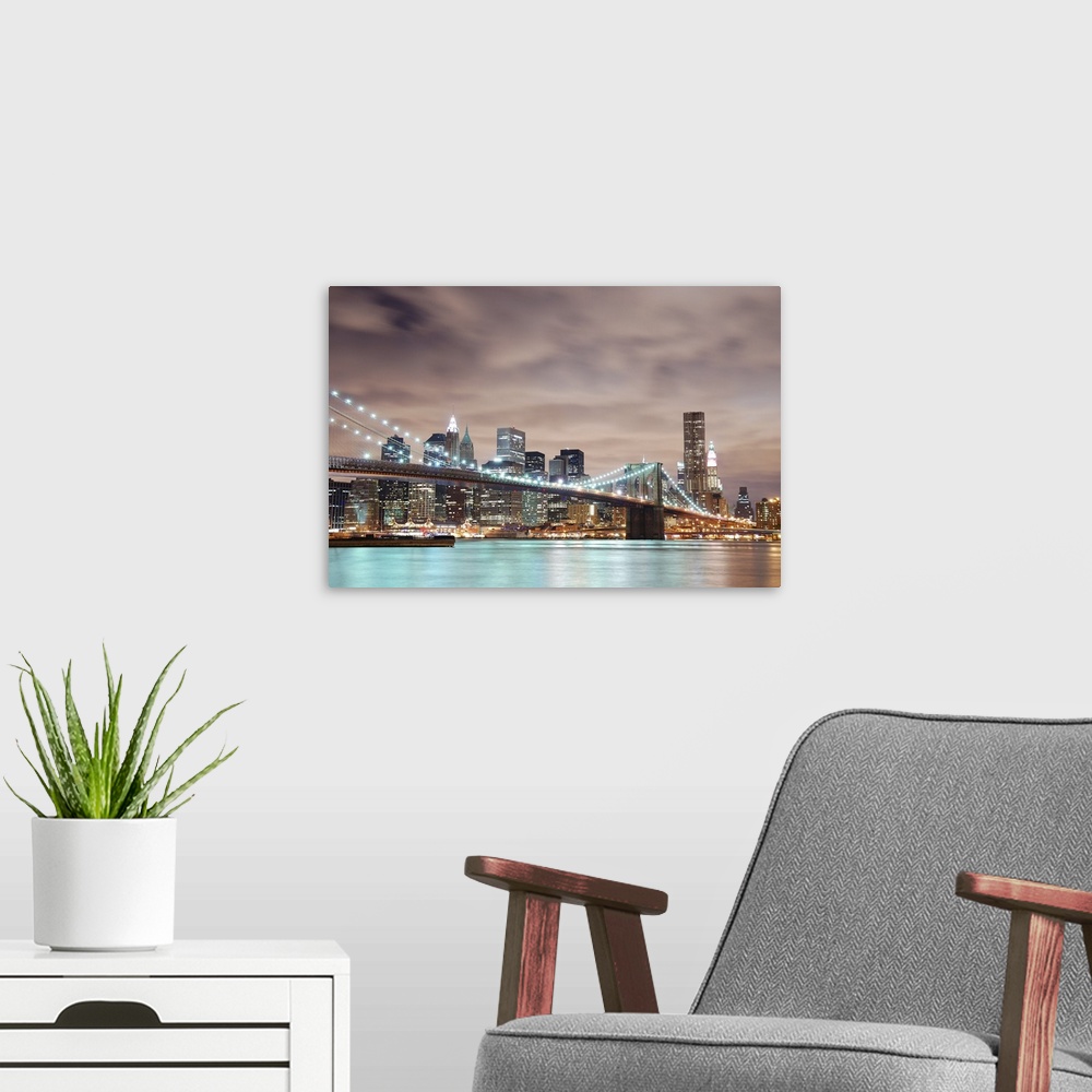 A modern room featuring Panoramic view of Manhattan with Brooklyn Bridge at night and skyscrapers illuminated over Hudson...