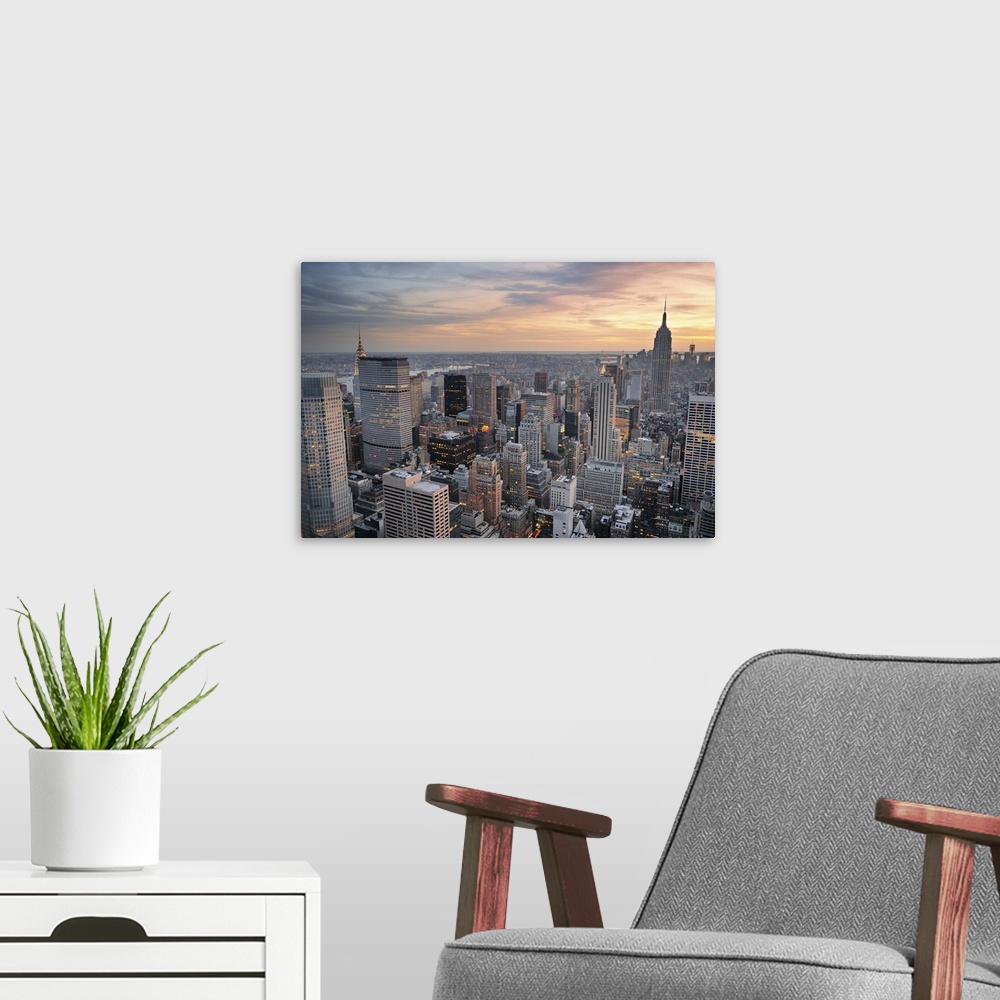 A modern room featuring New York City skyline aerial view at sunset with colorful cloud and skyscrapers of midtown Manhat...