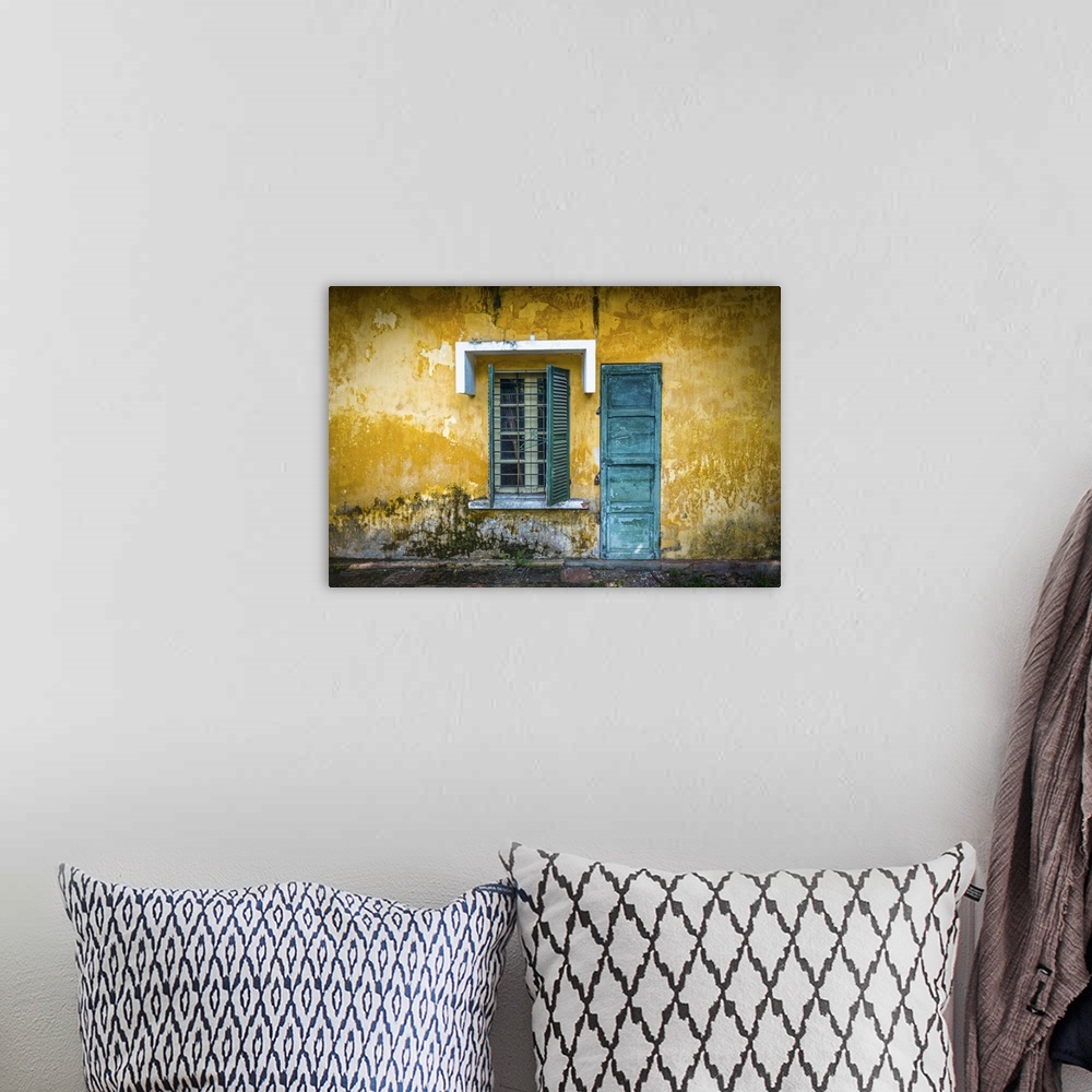 A bohemian room featuring Outside view of deserted house with details in Vietnam. Old and grungy yellow wall with window an...