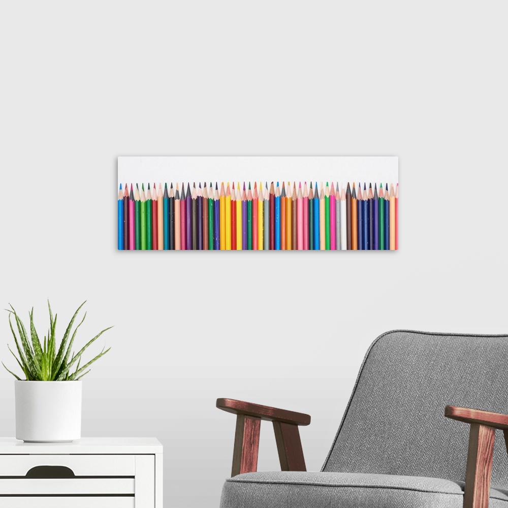 A modern room featuring Panoramic shot of straight line of color pencils isolated on white.