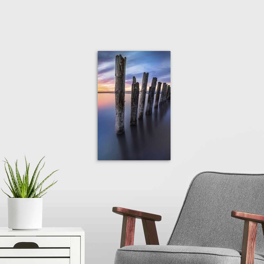 A modern room featuring Unusual pillars in the water on the background of colorful sky with bright clouds.