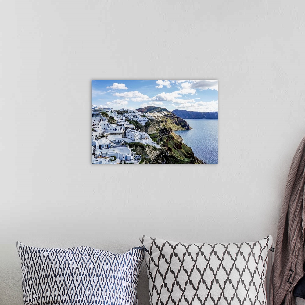 A bohemian room featuring White houses near tranquil sea against sky with clouds in greece.