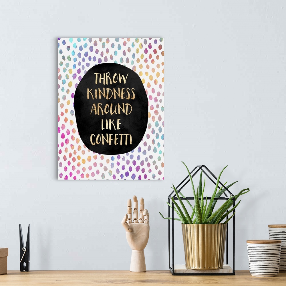 A bohemian room featuring The words 'throw kindness around like confetti' in gold letters on a black oval, surrounded by ra...