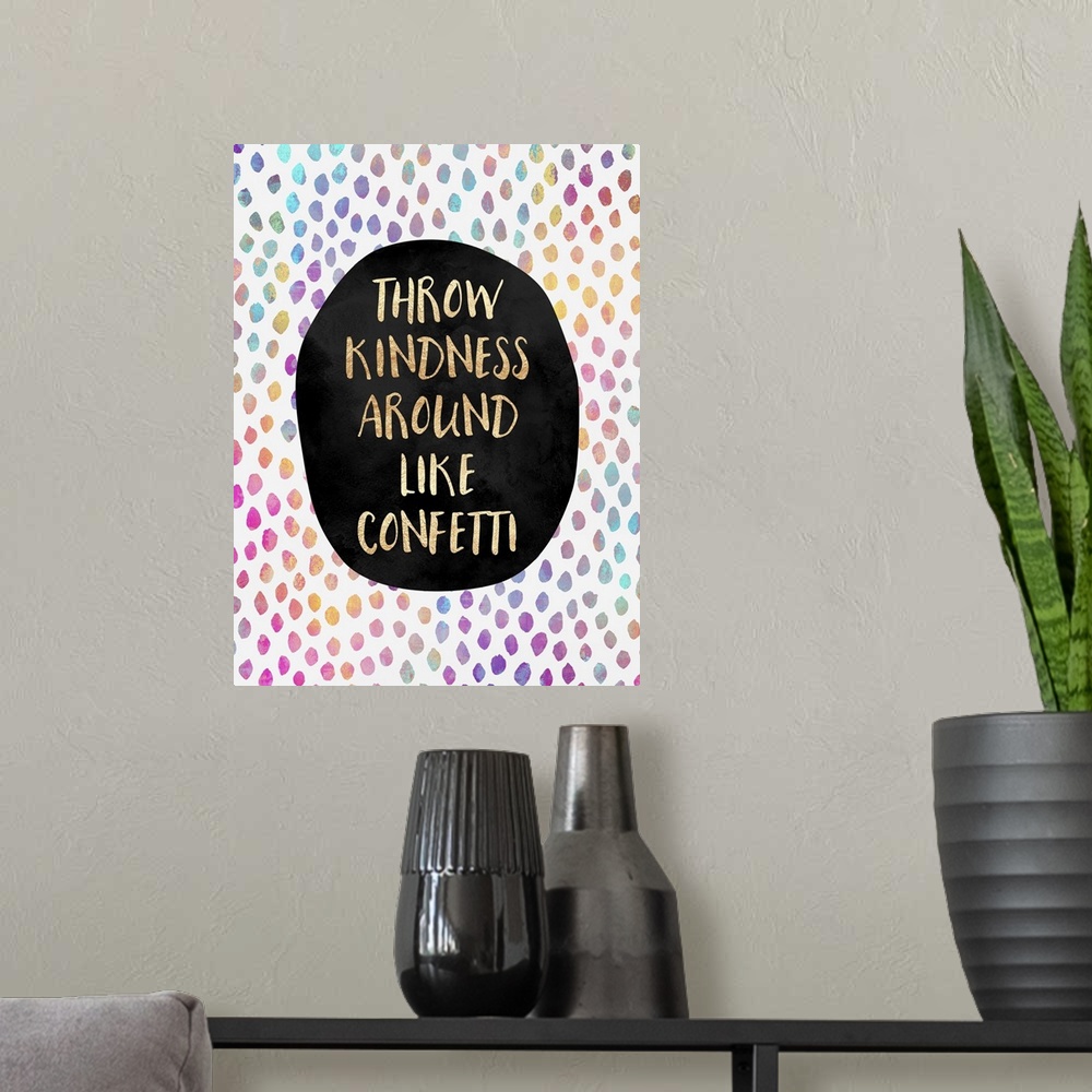 A modern room featuring The words 'throw kindness around like confetti' in gold letters on a black oval, surrounded by ra...