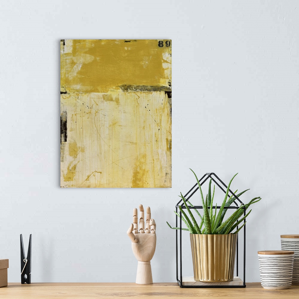 A bohemian room featuring A contemporary abstract painting using two tones of yellow meeting face to face.