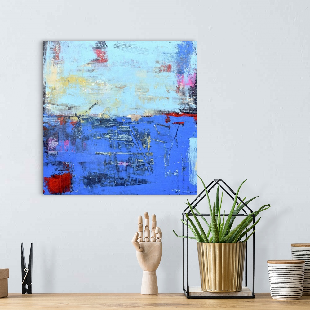 A bohemian room featuring A contemporary abstract painting using a dark and light blue meeting face to face.