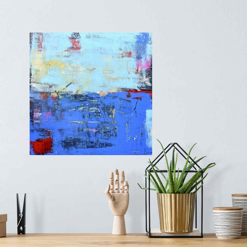 A bohemian room featuring A contemporary abstract painting using a dark and light blue meeting face to face.