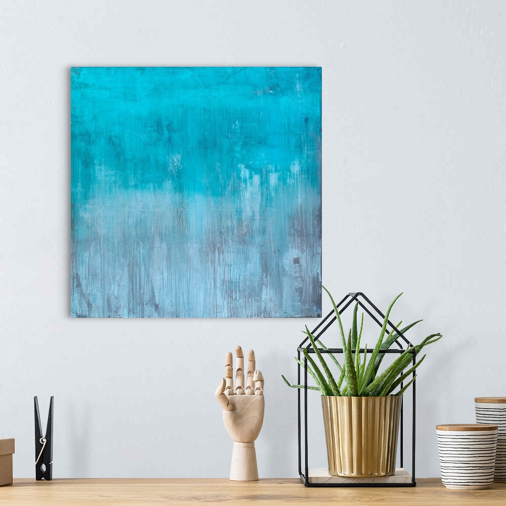 A bohemian room featuring Square abstract painting created with light blue turning into gray towards the bottom with streak...
