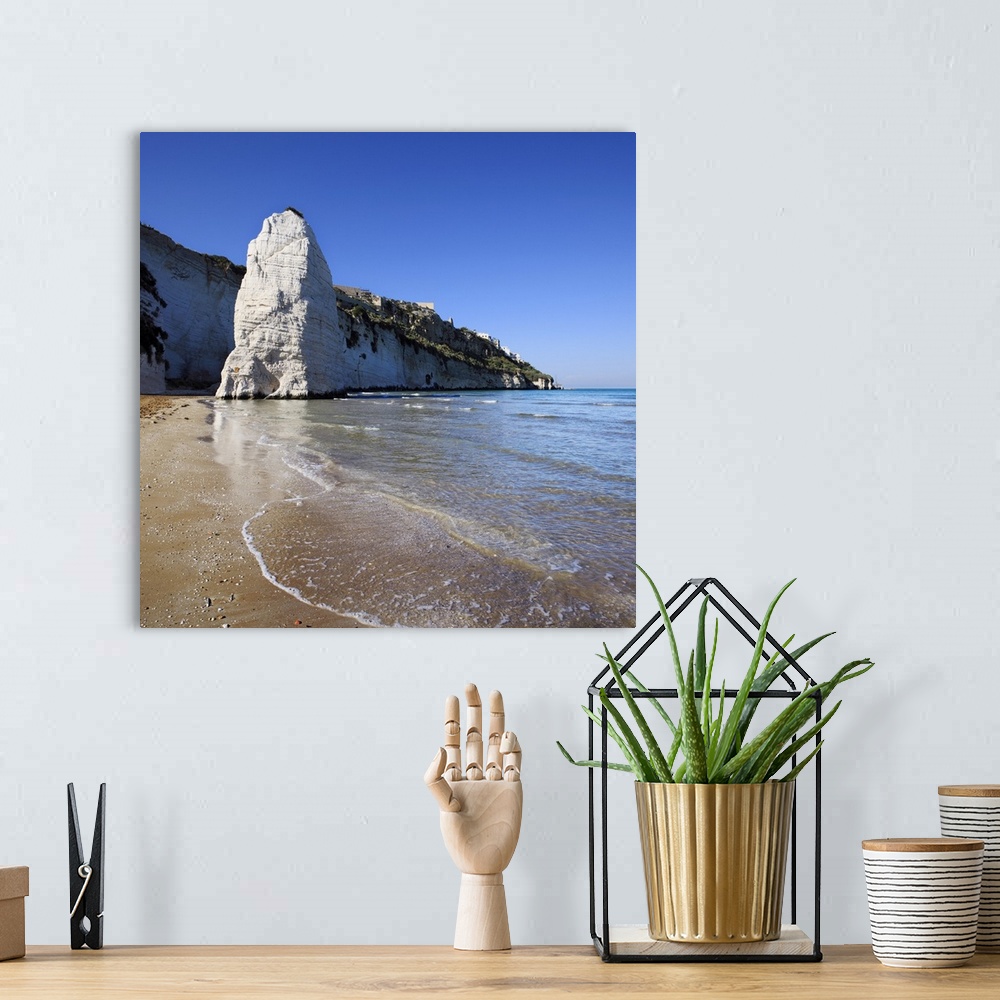 A bohemian room featuring Italy, Apulia, Gargano, Vieste, Pizzomunno rock and beach, with the town