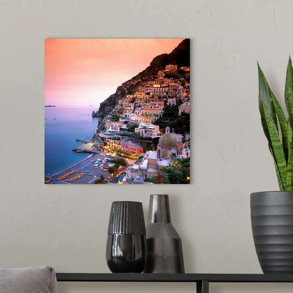 A modern room featuring A square shaped photograph of the charming Italian town of Positano at sunset. Built into the cli...